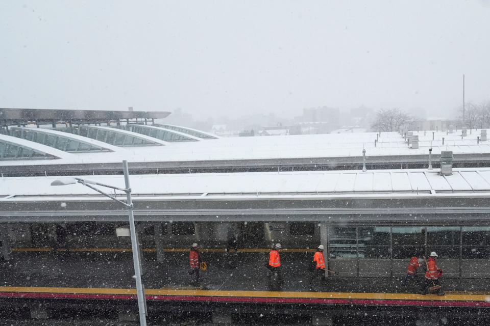 Workers walk along the platform at Long Island Rail Road Jamaica Station platform as snow falls at John F. Kennedy International Airport Tuesday (AP)