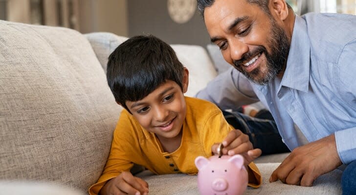 Father and son put money in a piggy bank