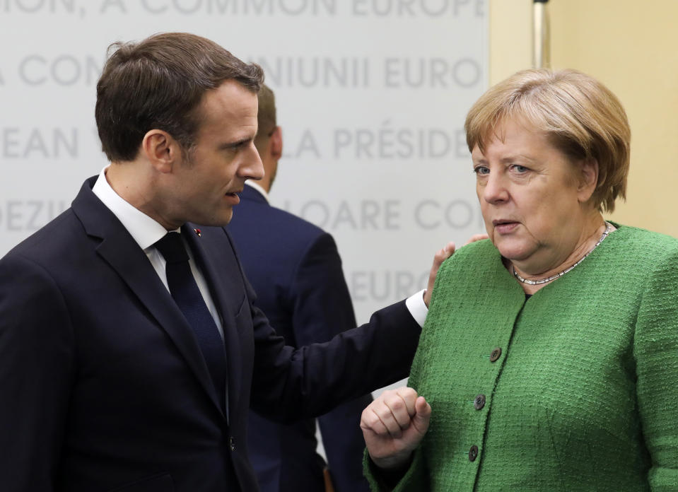 German Chancellor Angela Merkel, right, speaks with French President Emmanuel Macron, center, during a round table meeting at an EU summit in Sibiu, Romania, Thursday, May 9, 2019. European Union leaders on Thursday start to set out a course for increased political cooperation in the wake of the impending departure of the United Kingdom from the bloc. (Ludovic Marin, Pool Photo via AP)