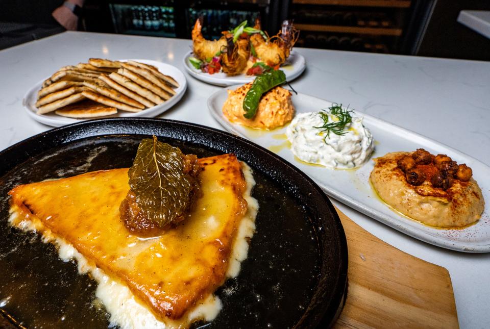 Saganaki (bottom), made with graviera cheese, lemon and honey-peppered fig, is on the meze menu at Avli. Kataifi Prawns (top), also on the meze menu, are made with kataifi filo, prawns, Mediterranean chopped salad and spicy aioli. The Sampler (middle) comes with three spreads of your choice and pita bread.