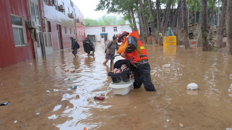 Firefighter evacuates a baby stranded by floodwaters in Fangshan district of Beijing