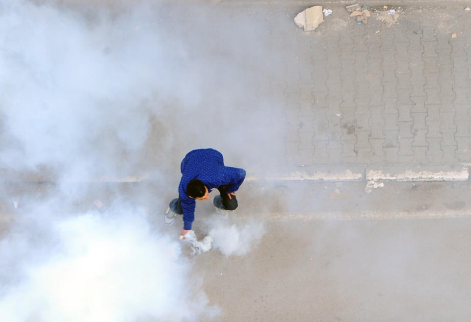 A protestor picks up a gas canister during a protest to denounce the Islamist-led government, in Tunis, Saturday, Feb,25, 2012. The demonstration was prompted by attacks on the union's offices around the country, which it blamed on members of Ennahda, the moderate Islamist party that won elections in October. (AP Photo/Hassene Dridi)
