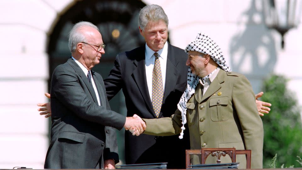 Clinton stands between the Palestinian leader Yasser Arafat and Israeli Prime Minister Yitzahk Rabin as they shake hands for the first time on September 13, 1993, at the White House. - J. David Ake/AFP/Getty Images