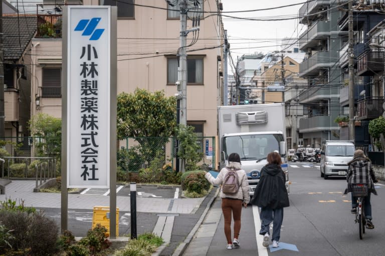 Una mujer señala el cartel de la sede de la compañía japonesa Kobayashi Pharmaceutical, el 28 de marzo de 2024 en Tokio (Yuichi Yamazaki)