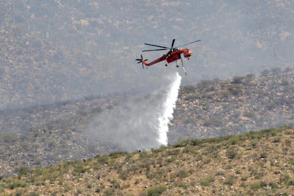 Heat ripples distort an air attack crew as they drop water on the Bighorn Fire along the western side of the Santa Catalina Mountains, Friday, June 12, 2020, in Oro Valley, Ariz. Hundreds of homes on the outskirts of Tucson remain under an evacuation notice as firefighters work to keep the wildfire from moving downhill from canyons and ridges in the Coronado National Forest. (AP Photo/Matt York)