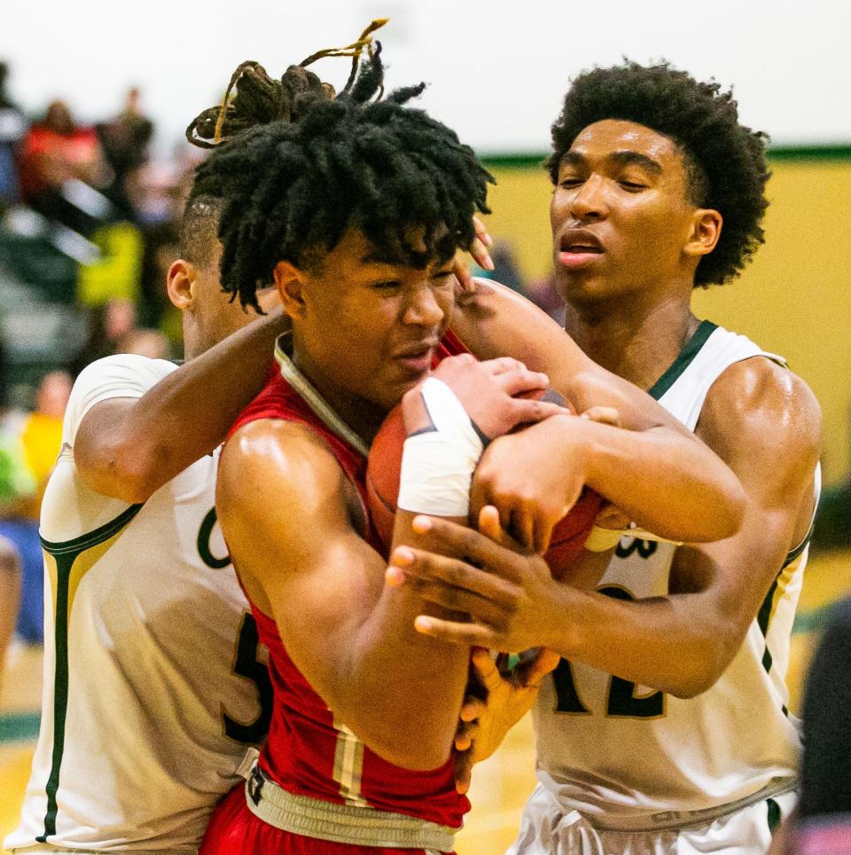 Bishop Snyder guard Trenton Walker (3) battles for control of the ball with two Ocala Trinity Catholic defenders during a February basketball playoff.