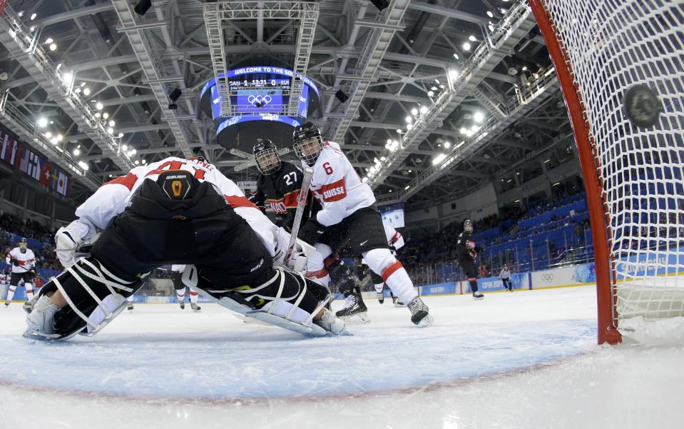 Canada's Watchorn scores on Switzerland's goalie Schelling while Switzerland's Marty defends during the first period of their women's ice hockey game at the 2014 Sochi Winter Olympics