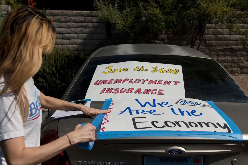 Francis Stallings tapes signs to her car before participating in a caravan rally down the Las Vegas Strip in support of extending the $600 unemployment benefit, August 6, 2020 in Las Vegas, Nevada. (Photo by Bridget BENNETT / AFP) (Photo by BRIDGET BENNETT/AFP via Getty Images)