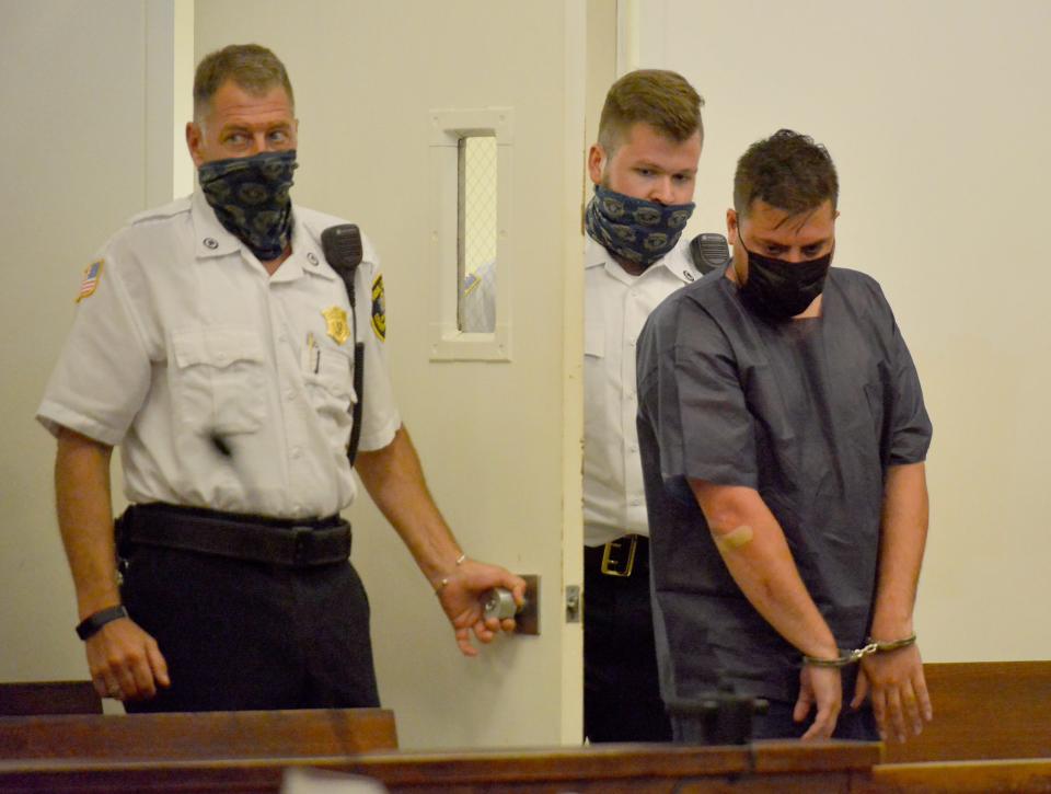 Michael Harrington, right, is escorted into the main session courtroom at Barnstable District Court Aug. 20, 2021, for his arraignment on charges in the stabbing attack on a woman outside her Barnstable home two days earlier. He was sentenced to 10-12 years on Wednesday after pleading guilty to charges related to the attack.