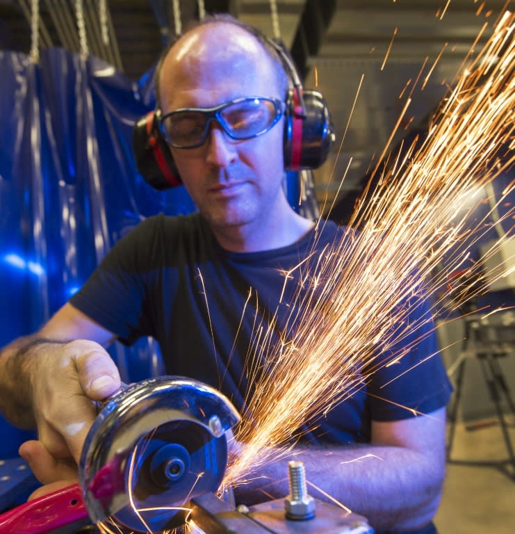 Metal shop instructor Tony Ritchie uses a grinder on a bicycle frame he is modifying, at TechShop in Arlington, Virginia