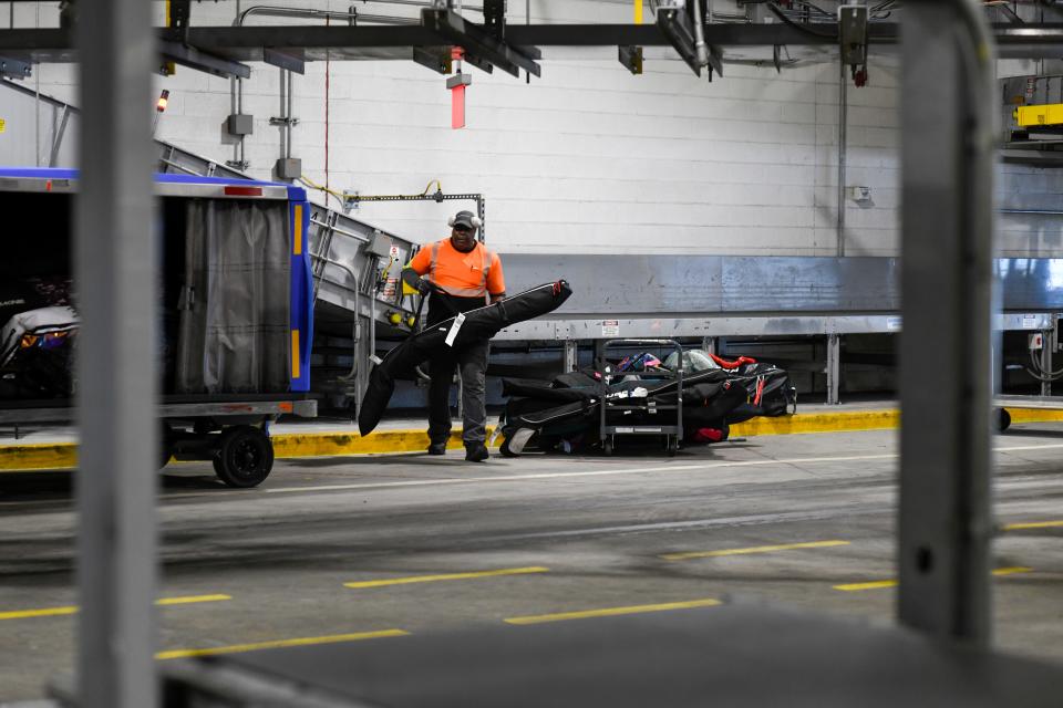An employee loads oversided bags onto a cart at LaGuardia Airport.