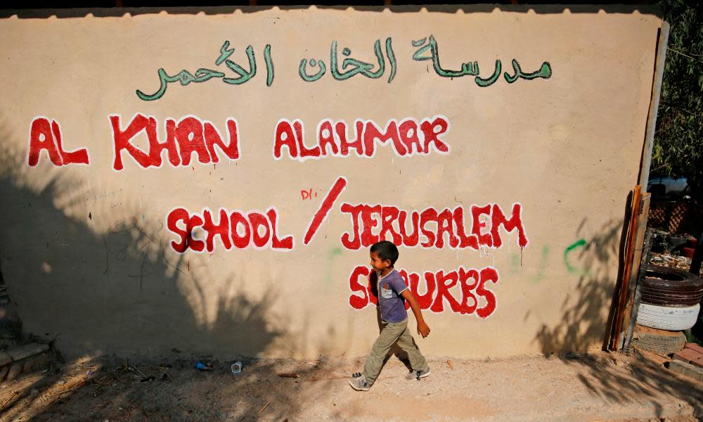 A Palestinian child walks past the wall of the school in Khan al-Ahmar