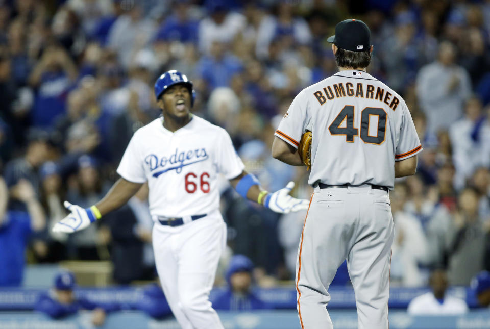 San Francisco Giants starting pitcher Madison Bumgarner, right, and Los Angeles Dodgers' Yasiel Puig, left, exchange words as Puig runs down the third base line after hitting a solo home run during the sixth inning of a baseball game, Friday, May 9, 2014, in Los Angeles. (AP Photo/Danny Moloshok)