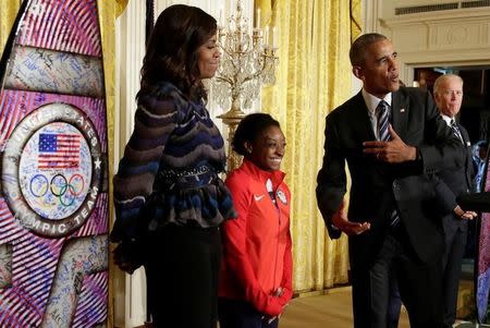 U.S. President Barack Obama gestures next to 2016 Olympic individual all-around gymnast Simone Arianne Biles as First lady Michelle Obama and Vice President Joe Biden look on to welcome U.S. Olympic and Paralympics teams at the White House in Washington, U.S., September 29, 2016. REUTERS/Yuri Gripas