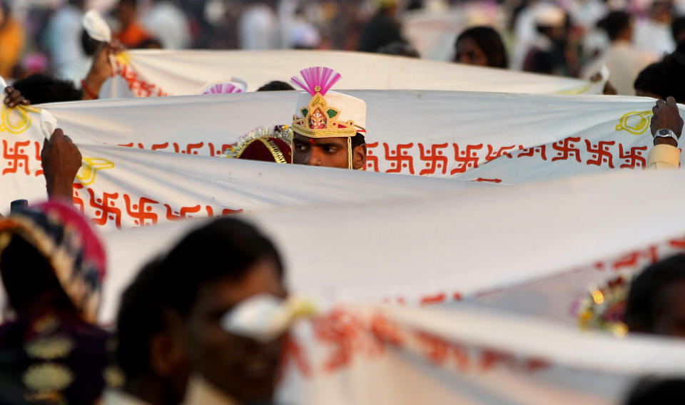 FILE - A groom stands behind a sheet bearing the Hindu swastika during a ritual at a mass wedding ceremony in Virar, on the outskirts of Mumbai, India, Sunday, Jan. 29, 2012. More than 1000 couples were married during the event that was organized by a local politician. (AP Photo/Rajanish Kakade)