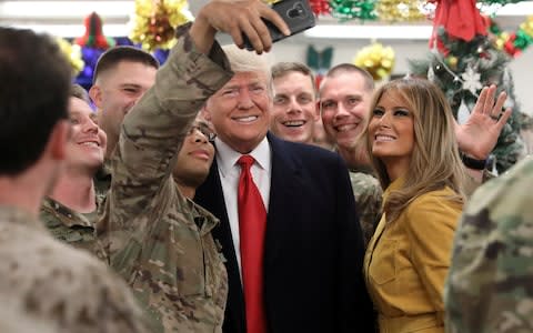 Donald Trump and Melania posing for selfies with US troops during a surprise visit to Iraq - Credit: JONATHAN ERNST/REUTERS 