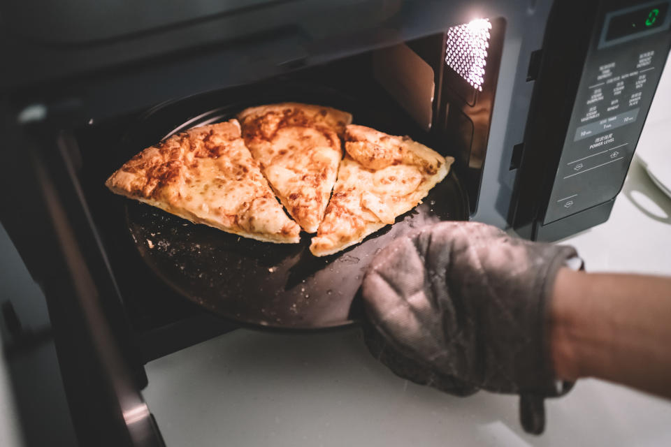 Removing pizza slices from the microwave.