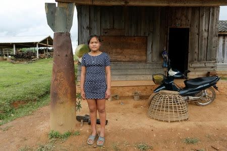 A girl poses at an entrance of her house next to a bomb dropped by the U.S. Air Force planes during the Vietnam War, in the village of Ban Napia in Xieng Khouang province, Laos September 3, 2016. REUTERS/Jorge Silva