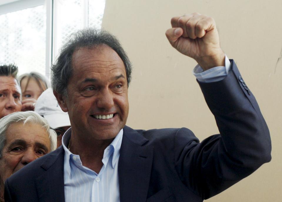 Presidential candidate Daniel Scioli of the ruling Front for Victory raises a fist after voting at a polling station during a presidential election in Buenos Aires, November 22, 2015. Argentines voted on Sunday in a run-off election that hands the center-right opposition, led by Mauricio Macri, its best chance in more than a decade to wrest the presidency from the populist Peronists. A win by Macri would set Argentina's spluttering economy on a more free-market course that he promises would rebuild investor confidence. Outgoing President Fernandez who was preceded in office by her late husband Nestor Kirchner, is as revered by the poor for her generous welfare programs as she is reviled by business for the strict controls the couple put on the economy during their 12 years in power. REUTERS/Martin Acosta