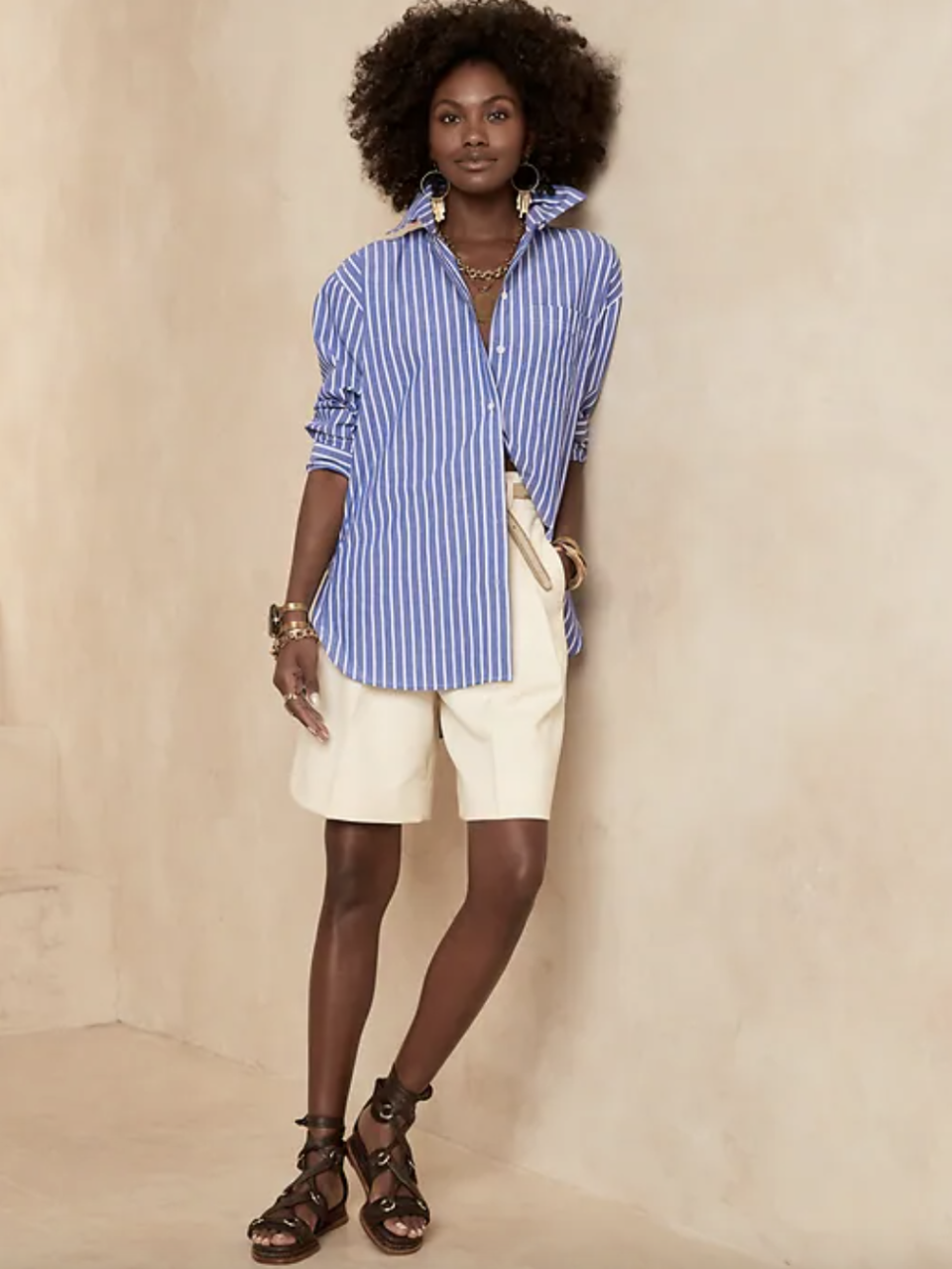 black model with afro wearing white shorts and blue and white striped Oversized Poplin Shirt (Photo via Banana Republic)