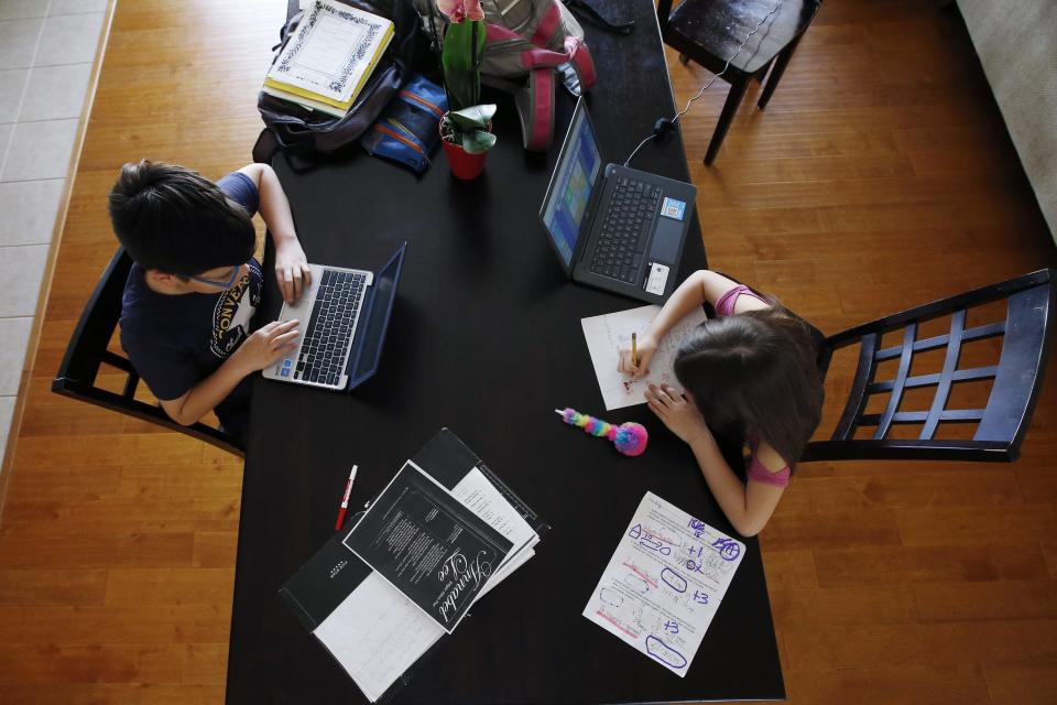 Tony Berastegui, left, and his sister Giselle, age 12 and nine respectively, do their school work at home on the dining room table as the COVID-19 coronavirus pandemic forced schools to close Monday, March 16, 2020, in Laveen, Ariz. (AP Photo/Ross D. Franklin)