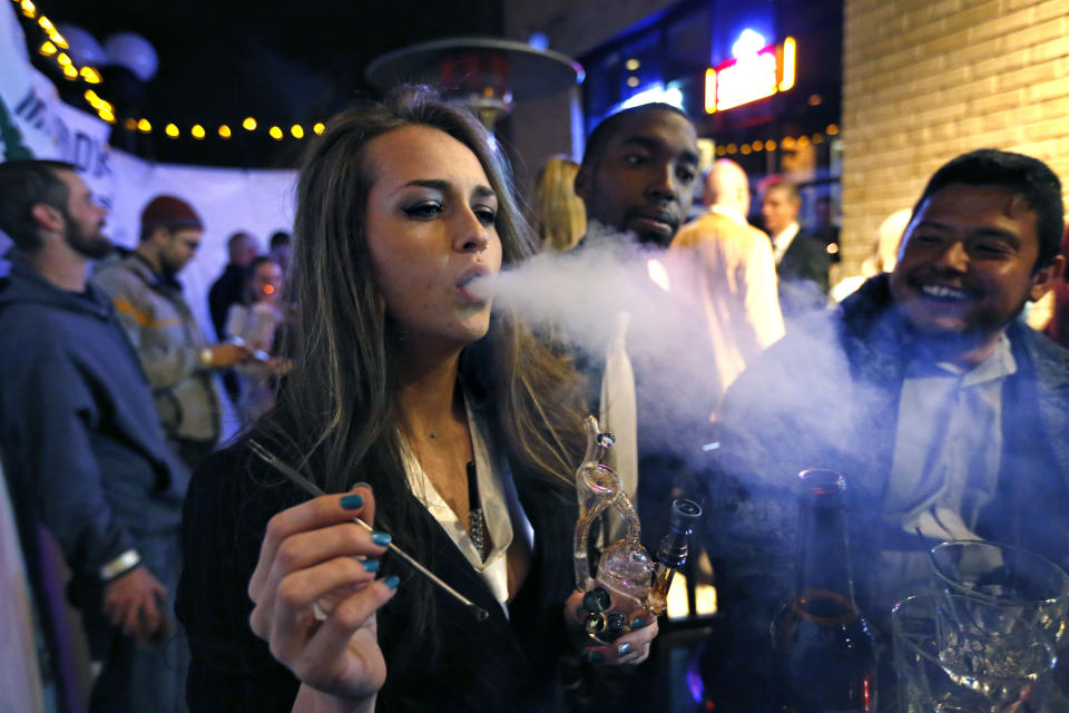 FILE - In this Tuesday evening, Dec. 31, 2013 file photo, a woman smokes marijuana during a Prohibition-era themed New Year's Eve party at a bar in Denver, the day before Colorado allowed retail sales of marijuana to those 21 and over. New research has found some Colorado teenagers who use marijuana are shifting away from smoking it in favor of edible products. About 78% of the Colorado high school students who reported consuming marijuana in 2017 said smoking was their usual method, down from 87% two years earlier. The number of teens who usually consumed edible marijuana products climbed to about 10% from 2% in the same two-year span while the number of users dabbing increased to about 7.5% from 4%. (AP Photo/Brennan Linsley,File)