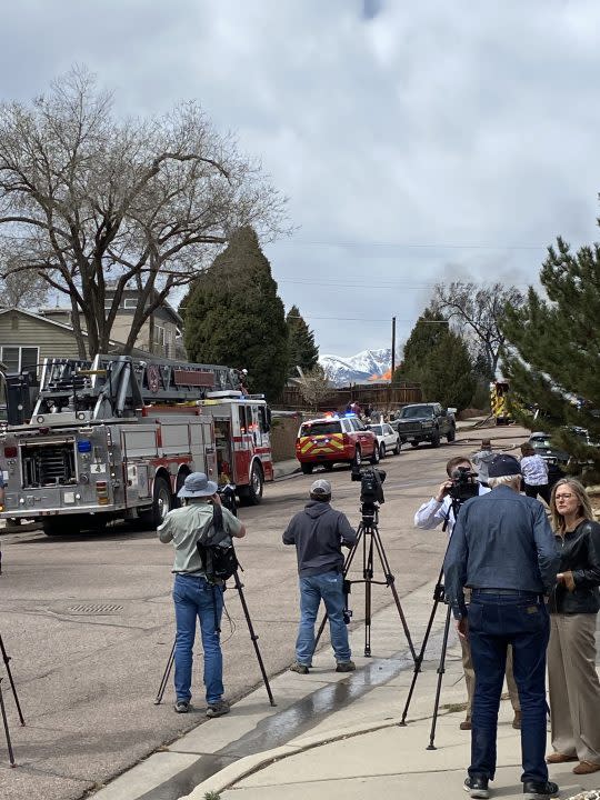 News crews and onlookers observe the fire