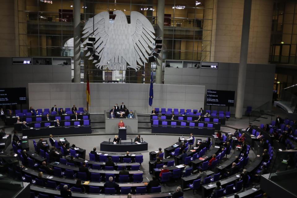 German Chancellor Angela Merkel, center in red dress, delivers her speech during the debate about Germany's budget 2021, at the parliament Bundestag in Berlin, Germany, Wednesday, Dec. 9, 2020. (AP Photo/Markus Schreiber)