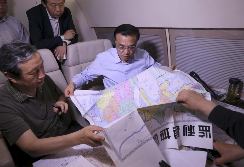 China's Premier Li Keqiang (R) looks at a map as he discusses with experts on a rescue plan, on his plane en route to the site where a ship sank in the Jianli section of Yangtze River, Hubei province, China, June 2, 2015. Some passengers are still alive inside the hull of a passenger ship carrying 458 people, many of them elderly Chinese tourists, that capsized on the Yangtze River, state media said on Tuesday. The ship capsized in a storm late on Monday. Only about a dozen people had been rescued so far, state media said amid confusing reports about how many had been saved. (REUTERS/cnsphoto)