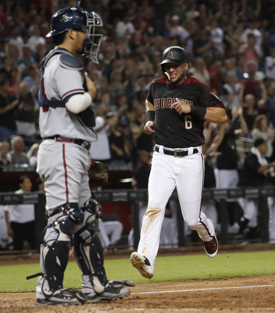 Arizona Diamondbacks' David Peralta scores on a double by Daniel Descalso during the eighth inning of a baseball game as Atlanta Braves catcher Kurt Suzuki looks on, Saturday, Sept. 8, 2018, in Phoenix. (AP Photo/Matt York)