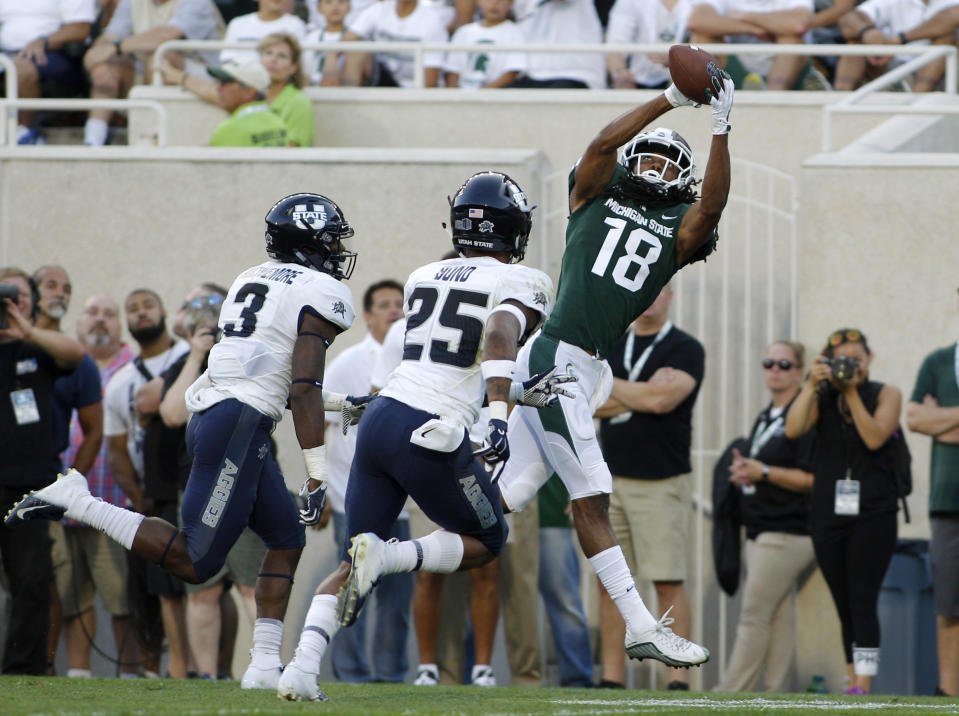 Michigan State's Felton Davis III (18) catches a pass against Utah State's Shaq Bond (25) and Jontrell Rocquemore (3) during the first quarter of an NCAA college football game, Friday, Aug. 31, 2018, in East Lansing, Mich. (AP Photo/Al Goldis)