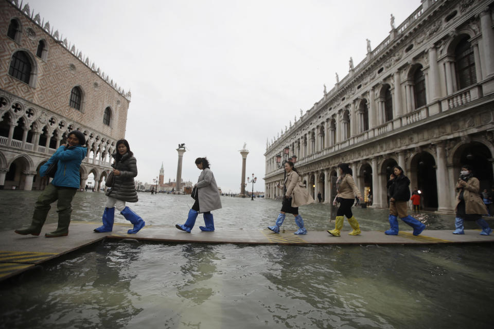 People use trestle bridges to walk in a flooded St. Mark's Square at Venice, Friday, Nov. 15, 2019.The high-water mark hit 187 centimeters (74 inches) late Tuesday, Nov. 12, 2019, meaning more than 85% of the city was flooded. The highest level ever recorded was 194 centimeters (76 inches) during infamous flooding in 1966. (AP Photo/Luca Bruno)