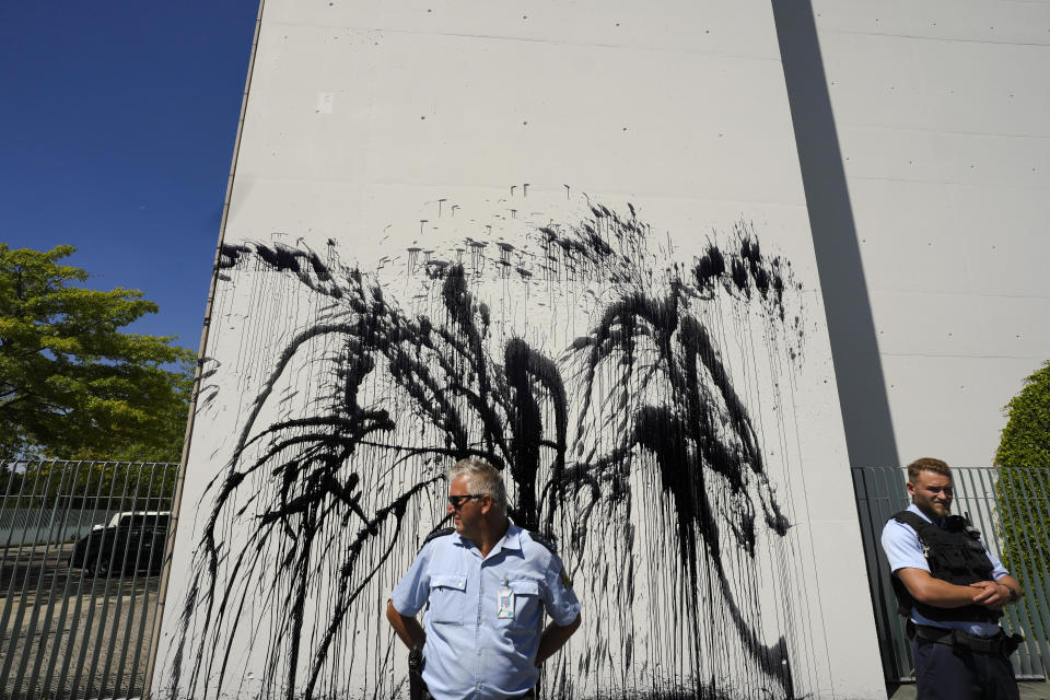 Police officers guard the chancellery after climate activists with the group Uprising of the Last Generation threw black paint on the chancellery in Berlin, Germany, Wednesday, June 22, 2022. The group claims the world has only a few years left to turn the wheel around and avoid catastrophic levels of global warming. (AP Photo/Markus Schreiber)