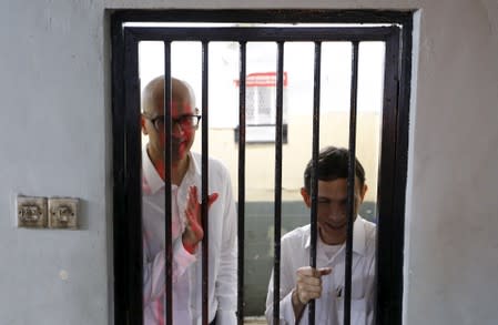 FILE PHOTO: Canadian teacher Neil Bantleman waves beside Indonesian teaching assistant Ferdinand Tjiong to students as they wait inside a holding cell before their trial at a South Jakarta court