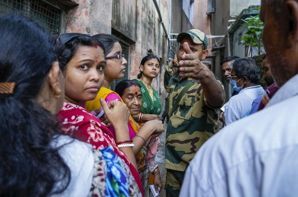 A Border Security Force soldier requests voters to stand in the queue outside a polling booth during the fifth round of multi-phase national election in Howrah, India, Monday, May 20, 2024. (AP Photo/Bikas Das)