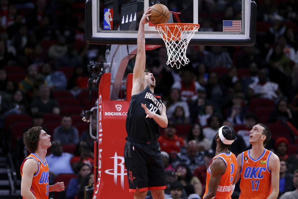 Houston Rockets center Alperen Sengun dunks over Oklahoma City Thunder guards Josh Giddey (3) and Shai Gilgeous-Alexander (2) and forward Aleksej Pokusevski (17) during the first half of an NBA basketball game Saturday, Nov. 26, 2022, in Houston. (AP Photo/Michael Wyke)