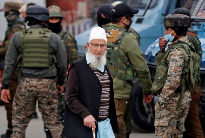 FILE PHOTO: A Kashmiri Muslim man walks past Indian security forces standing guard during a cordon and search operation, in Srinagar