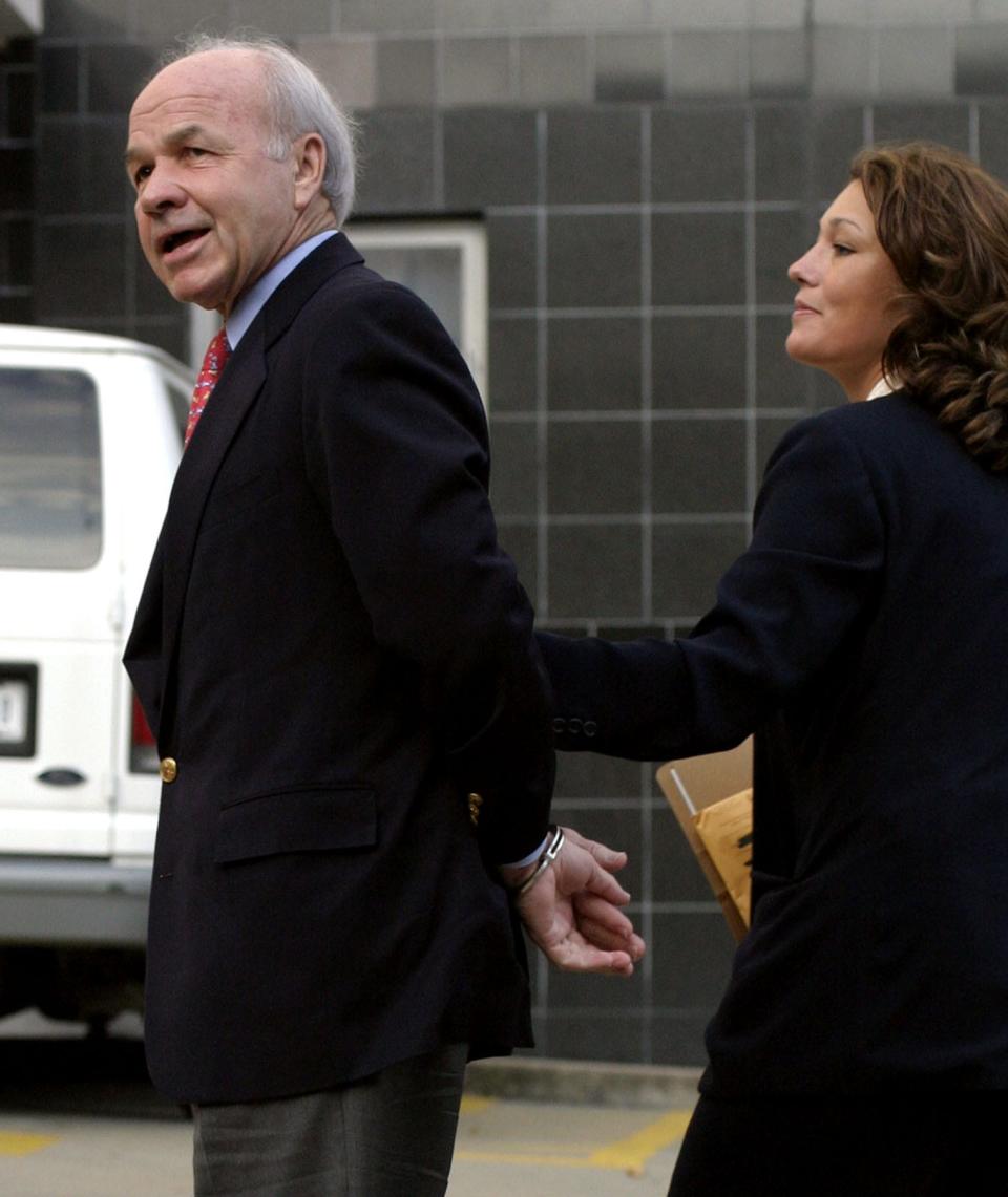 Former Enron CEO Ken Lay, left, is led into Federal Court by law enforcement officers in Houston after surrendering to the FBI in this July 8, 2004 file photo. Lay was a cheerleader for electric deregulation in Texas in the late 1990s. [AP Photo / Michael Stravato]