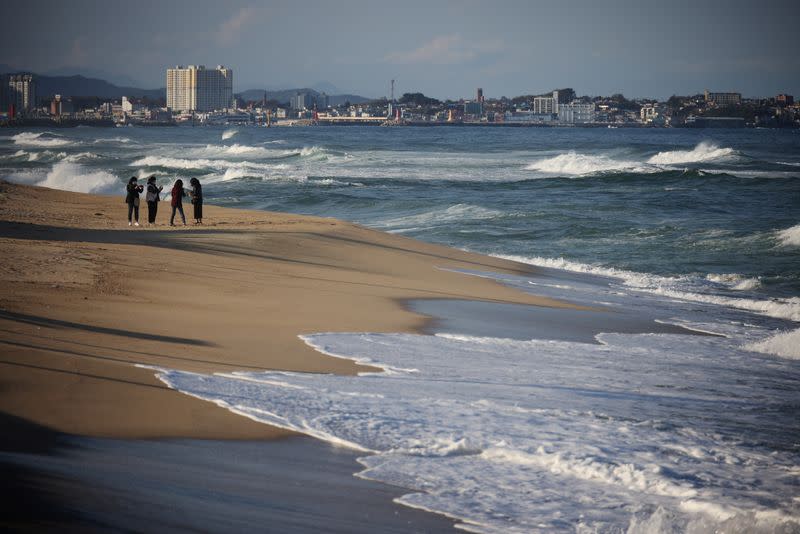 People stand at erosion-affected Sacheon beach where there used to be a long sand beach, in Gangneung