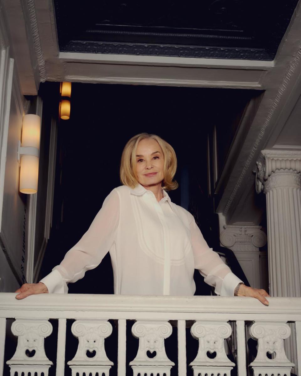 A woman poses upon a banister.