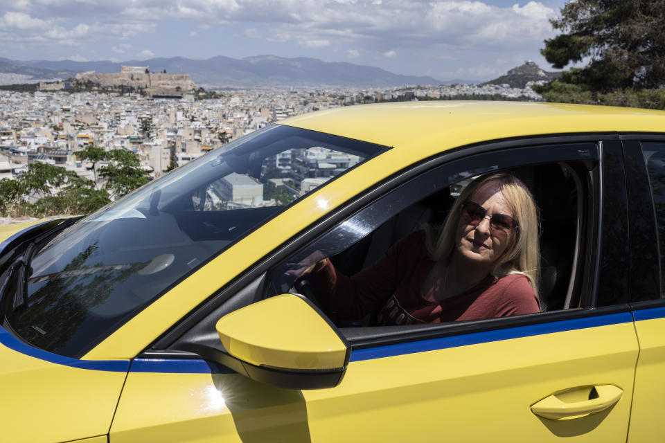 Cab driver Christina Messari looks out the window of her taxi, with the ancient Acropolis in the background, in Athens on Wednesday, May 17, 2023. 49-year-old Messari, who is in business with her husband, struggled during the pandemic, and delivered parcels to make ends meet. Greeks go to the polls Sunday, May 21, in the first general election held since the country ended successive international bailout programs and strict surveillance period imposed by European leaders. Conservative Prime Minister Kyriakos Mitsotakis is seeking a second four-year term and is leading in opinions but may need a coalition partner to form the next government. (AP Photo/Petros Giannakouris)