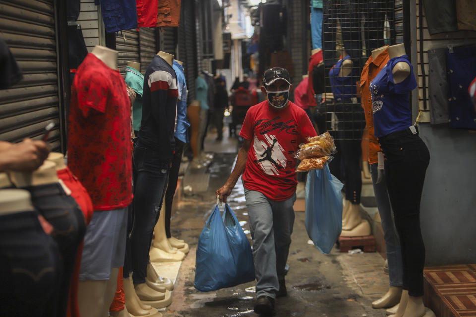 A man, wearing a protective face mask, walks through a popular market in Managua, Nicaragua, Tuesday, April 7, 2020. Restaurants are empty, there's little traffic in the streets and beach tourists are sparse headed into Holy Week despite the government's encouragement for Nicaraguans to go about their normal lives. (AP Photo/Alfredo Zuniga)