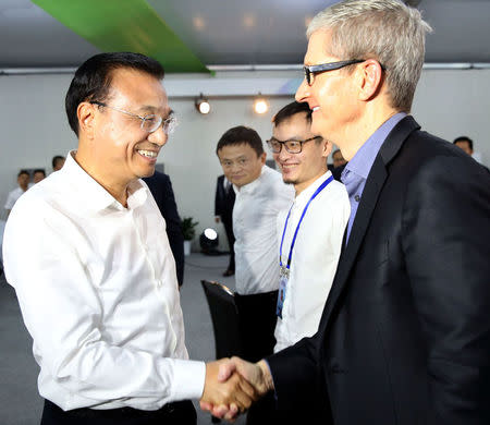 China's Premier Li Keqiang (L) shakes hands with Apple's chief executive Tim Cook (R) as Alibaba Group Holding Ltd founder Jack Ma (2nd, L) looks on during a nation-wide innovation event, in Shenzhen, Guangdong province, China, October 12, 2016. Picture taken October 12, 2016. China Daily/via REUTERS