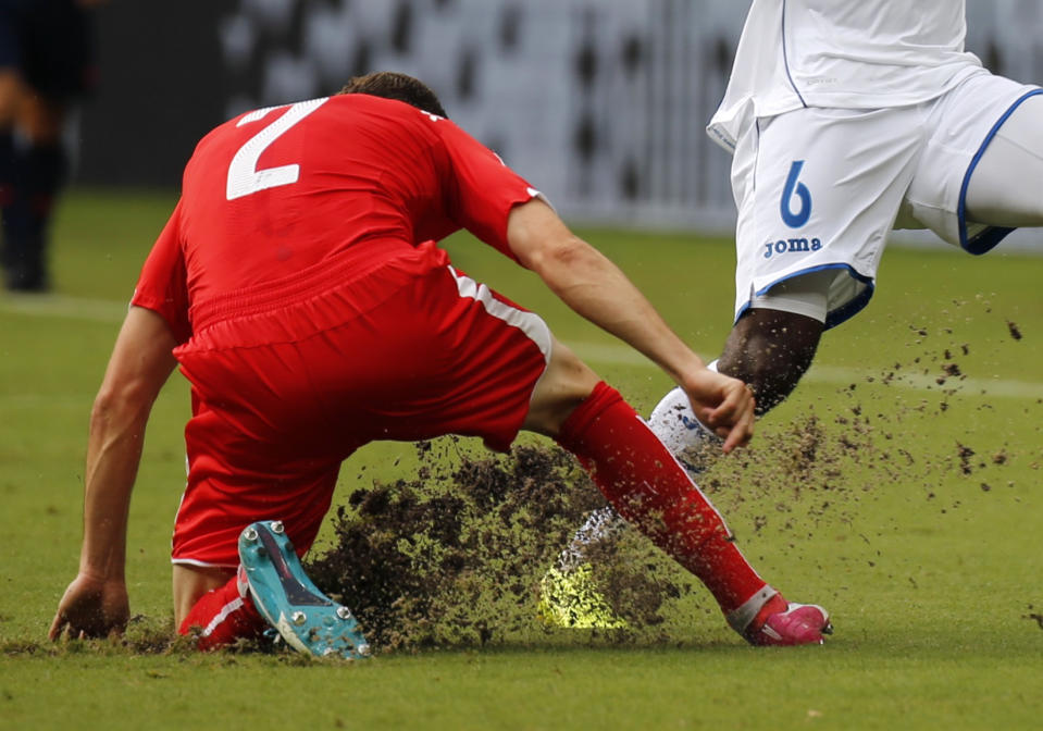 The field is dug up as Switzerland's Stephan Lichtsteiner (L) fights for the ball with Juan Carlos Garcia of Honduras during their 2014 World Cup Group E soccer match at the Amazonia arena in Manaus June 25, 2014. REUTERS/Siphiwe Sibeko (BRAZIL - Tags: SOCCER SPORT WORLD CUP)