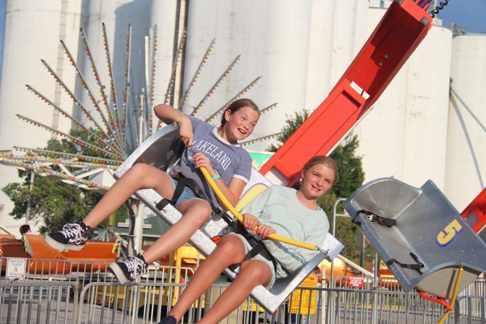 Brynn Senne, left, and Isabella Beyer have fun on a carnival ride during the Dallas Center Fall Festival on Friday, Aug. 26, 2022.