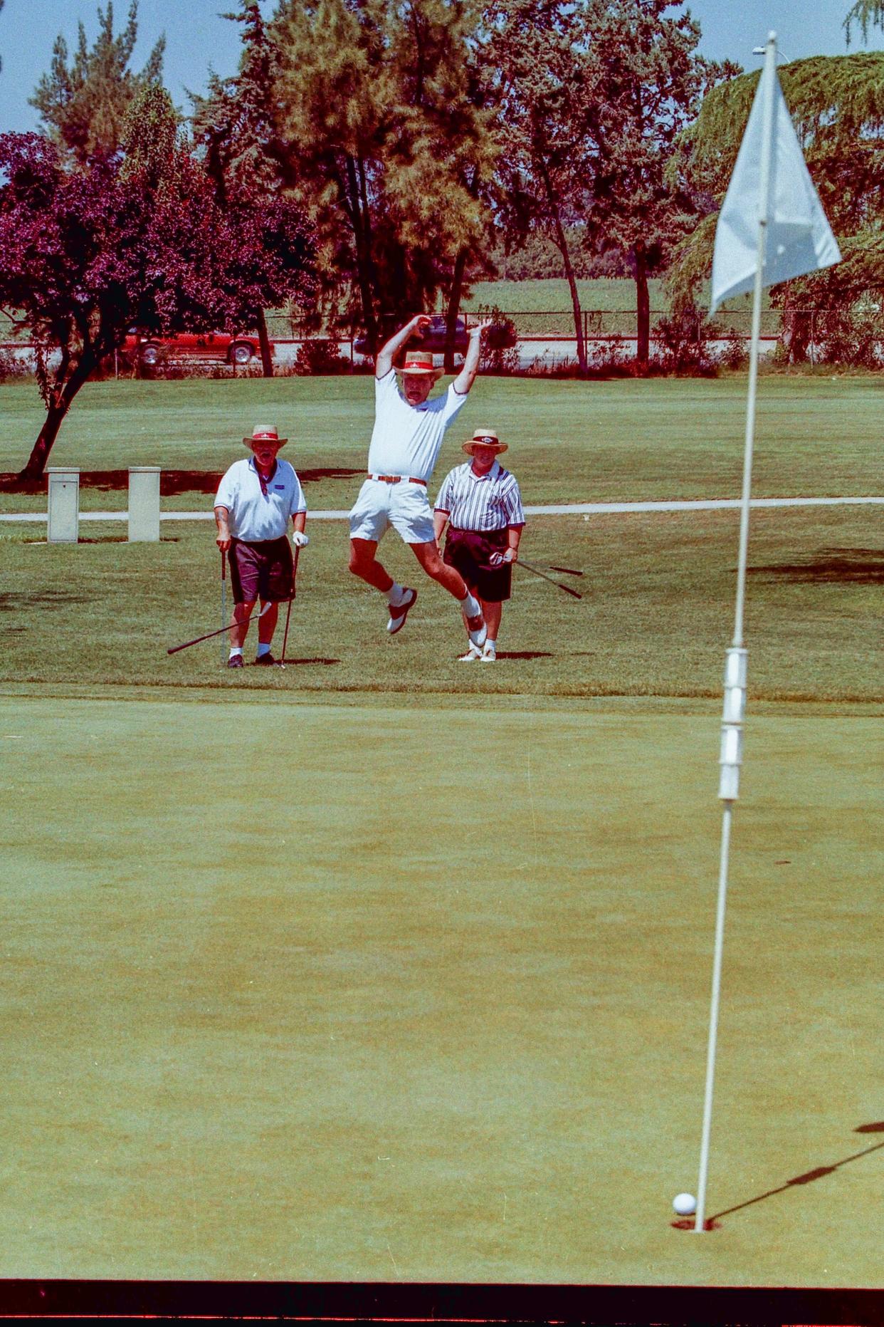 Bruce McDermott celebrates sinking a chip shot from off the green during a fund raiser at Visalia Country Club in July of 1998.