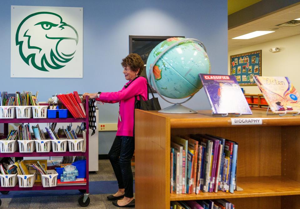 Carolyn Freeman, who works with IPS students through United Way's ReadUP program, pulls a cart full of books Tuesday, Nov. 7, 2023, into a workroom inside the library at Brookside Elementary School #54 in Indianapolis. For nearly 16 years, the ReadUP program has been connecting volunteers with elementary schools to get students on track with grade-level literacy.