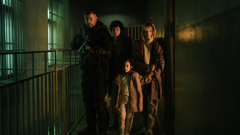 Tyler Rake leads a gangster's family down a prison hallway in Extraction 2