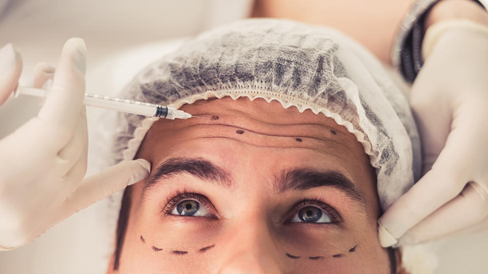 Handsome man is getting face skin treatment. Doctor in medical gloves is making an injection, close-up