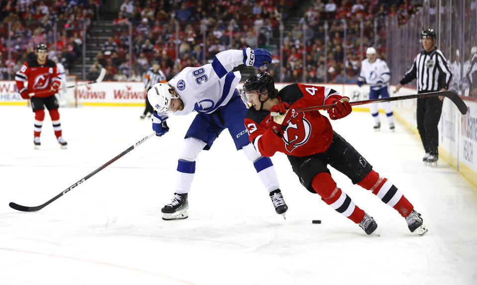 Tampa Bay Lightning left wing Brandon Hagel (38) and New Jersey Devils defenseman Luke Hughes (43) battle for the puck during the first period of an NHL hockey game, Sunday, Feb. 25, 2024, in Newark, N.J. (AP Photo/Noah K. Murray)